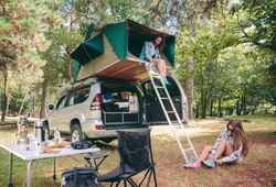 Woman in tent over 4x4 putting on hiking boots