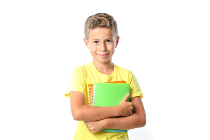 Boy in yellow t-shirt with copybooks isolated on blank background