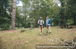 Two women friends with backpacks walking in forest 48B2zj