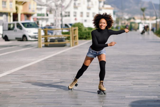 Happy woman with afro roller skating outside