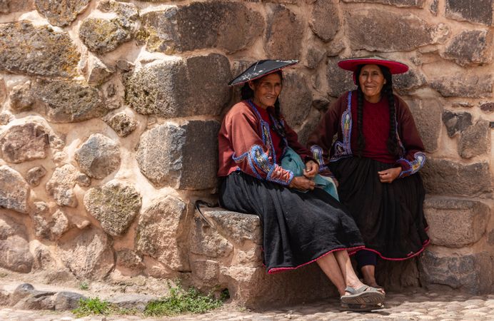 Peru - January, 02 2012: Peruvian women sitting near stone wall