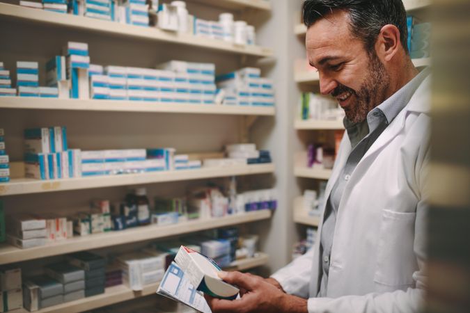 Pharmacist holding prescription and checking medicine in pharmacy