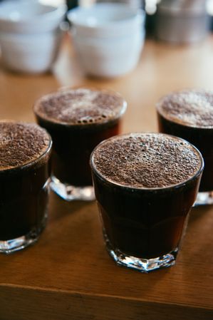Top view of four glasses with hot coffee with bubbles on top
