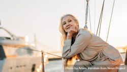 Happy older woman leaning on sailboat railings 5qoLEb
