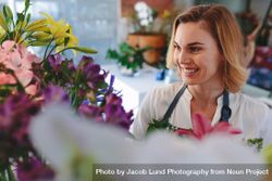 Smiling florist looking at flowers in her shop 4dNVA0
