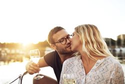 Couple kissing on a boat with wine glasses