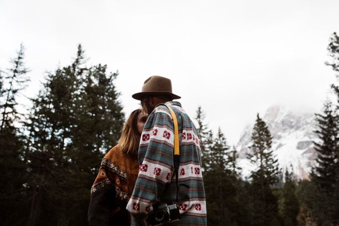 Casual resting couple standing in an embrace on route amid forest
