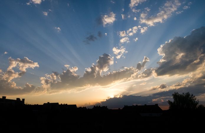 Sun behind clouds over rooftops