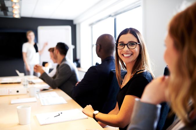 Woman looking at camera smiling and sitting in a boardroom