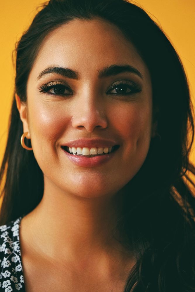 Headshot of happy Hispanic woman in yellow room, vertical