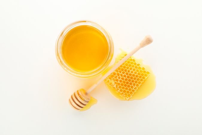Glass jar, honeycomb and dipper isolated on neutral background