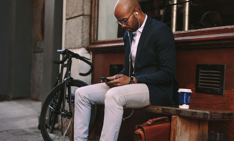 Young businessman sitting outdoors on a bench using phone