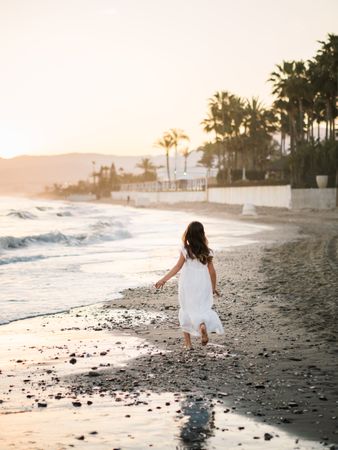 Adorable girl walking on seaside at sunset