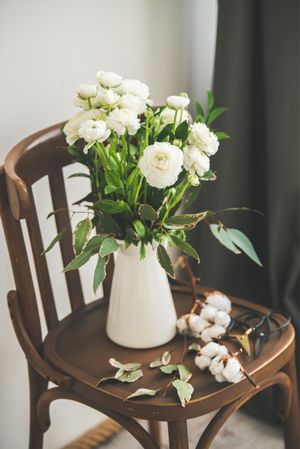 Spring buttercup flowers in enamel jug on chair