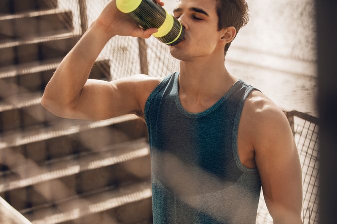 Muscular young man drinking water after workout