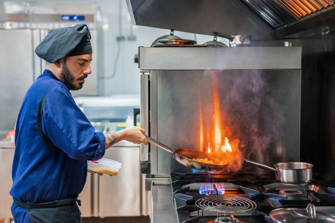 Chef cooking with flame in frying pan