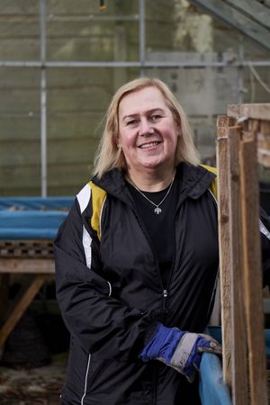 Woman smiling and looking at camera inside greenhouse