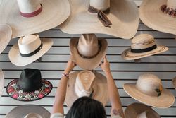 A young Hispanic woman is choosing a hat in a shop