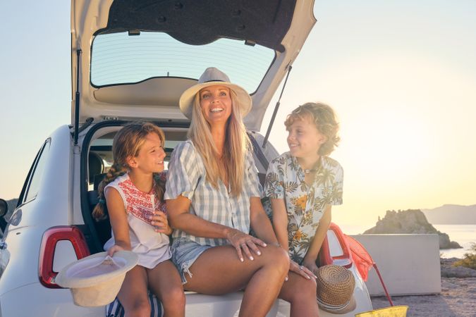 Mother with two children sitting in the trunk of a car during th