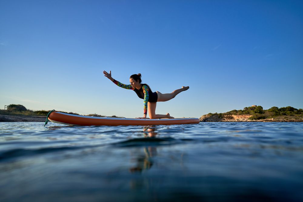 Concentrated woman practicing yoga on paddleboard