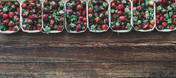 Strawberries in eco-friendly plastic-free boxes, lined up on wood background, copy space