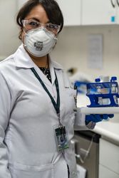 Female scientist in PPE holding a tray of samples 4OLyRb