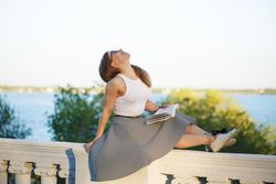 Woman perched atop a wall holding a book