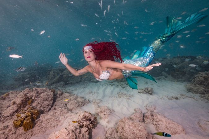 Redhead fairytale female mermaid swimming underwater