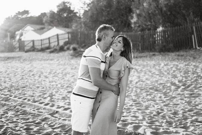 Laughing couple hugging on sandy beach