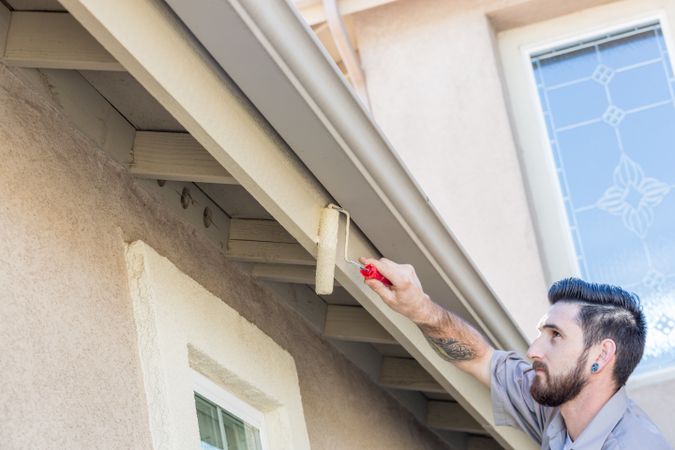 Professional Painter Using Small Roller to Paint House Fascia