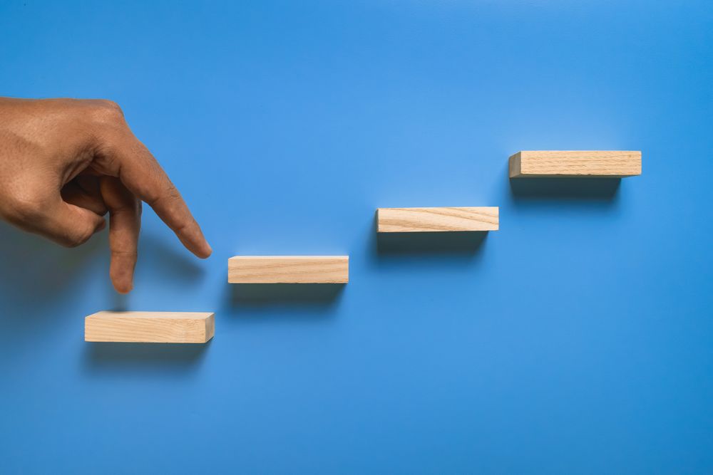 male hand walk on stairway wooden blocks isolated on blue background