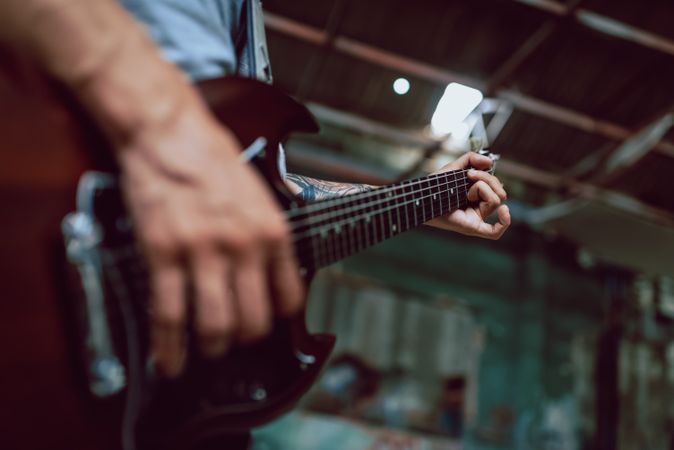 Man clamping strings on guitar neck
