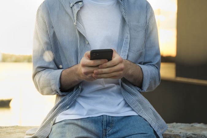 Young man uses a phone outdoor. Writing a message