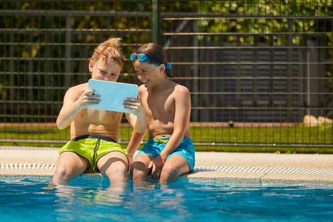 Boys on poolside browsing tablet