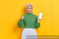 Woman in headscarf showing screen of her smart phone and giving the thumbs up bYx2Y4
