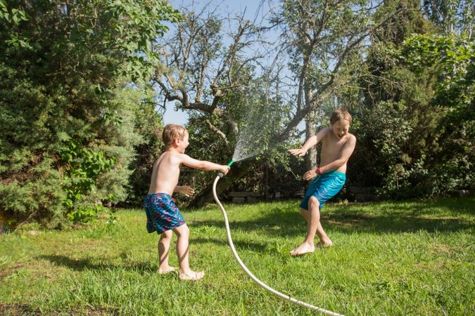 Little kids in swimwear having fun with splashing water
