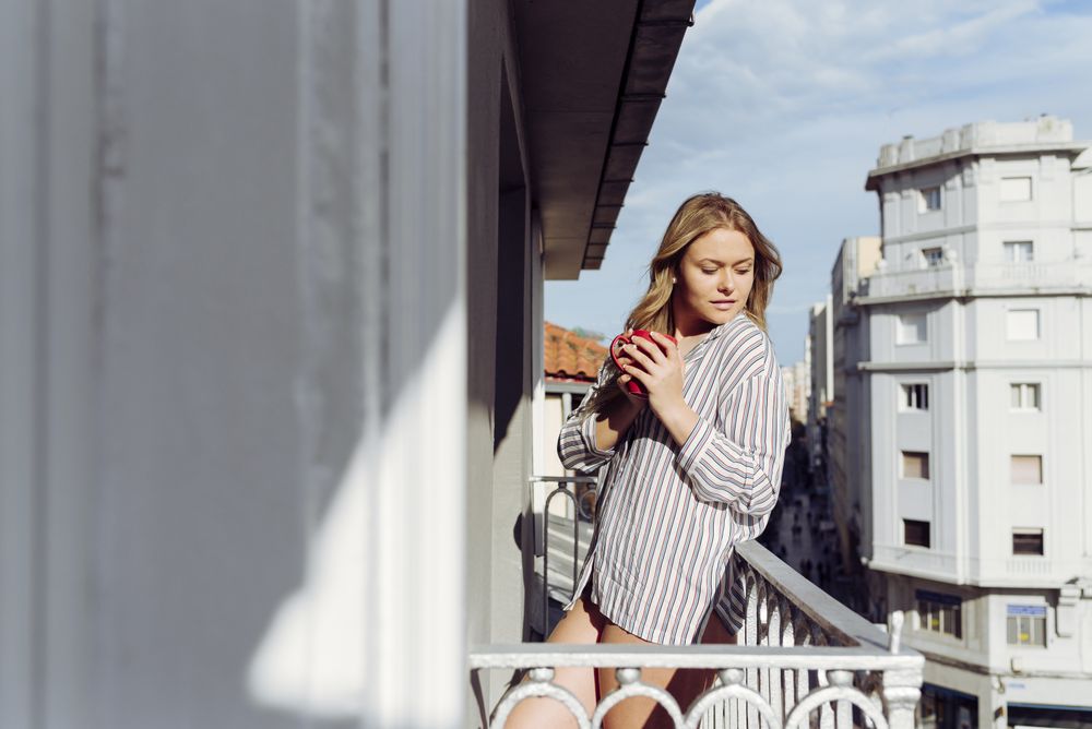 Young cheerful female with cup on terrace