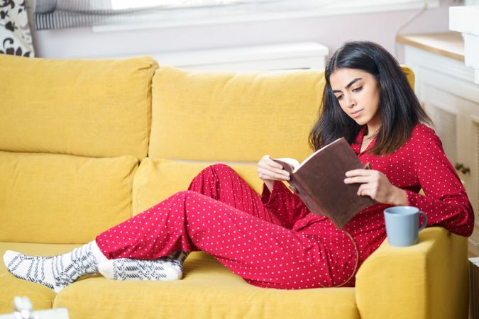 Female sitting in red pajamas at home reading book