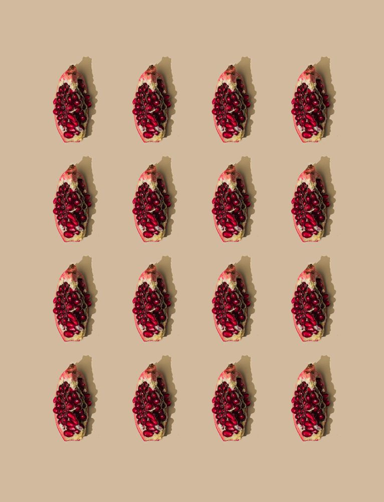 Pattern of pomegranate fruit slices and pastel sand background