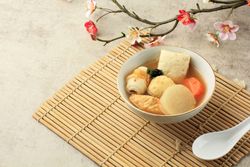 Bowl of Japanese oden served on placemat with flower