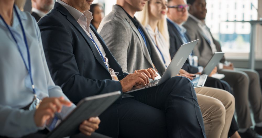 Close Up on Hands Of Man Sitting in Crowded Audience at Business Conference, Using Laptop. Delegate Watching Entrepreneurship Presentation About Developing Markets, Financial Opportunities.