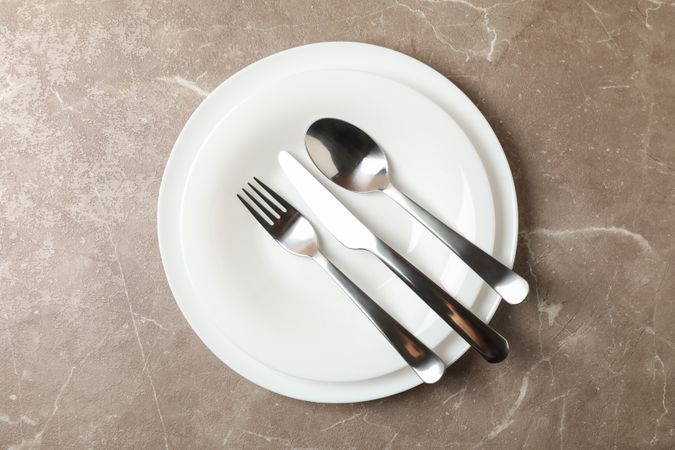 Plates with cutlery on gray background, top view