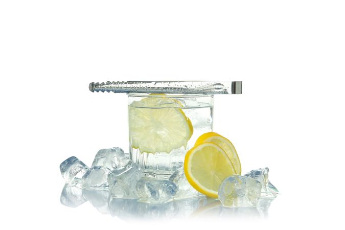 Rocks glass full of ice with lemon slice, with tongs on top