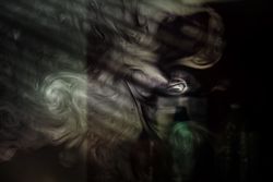 Swirls of smoke in a dark room with light coming in through the blinds