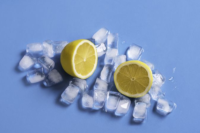 Fresh lemon sliced in half on melting ice cubes