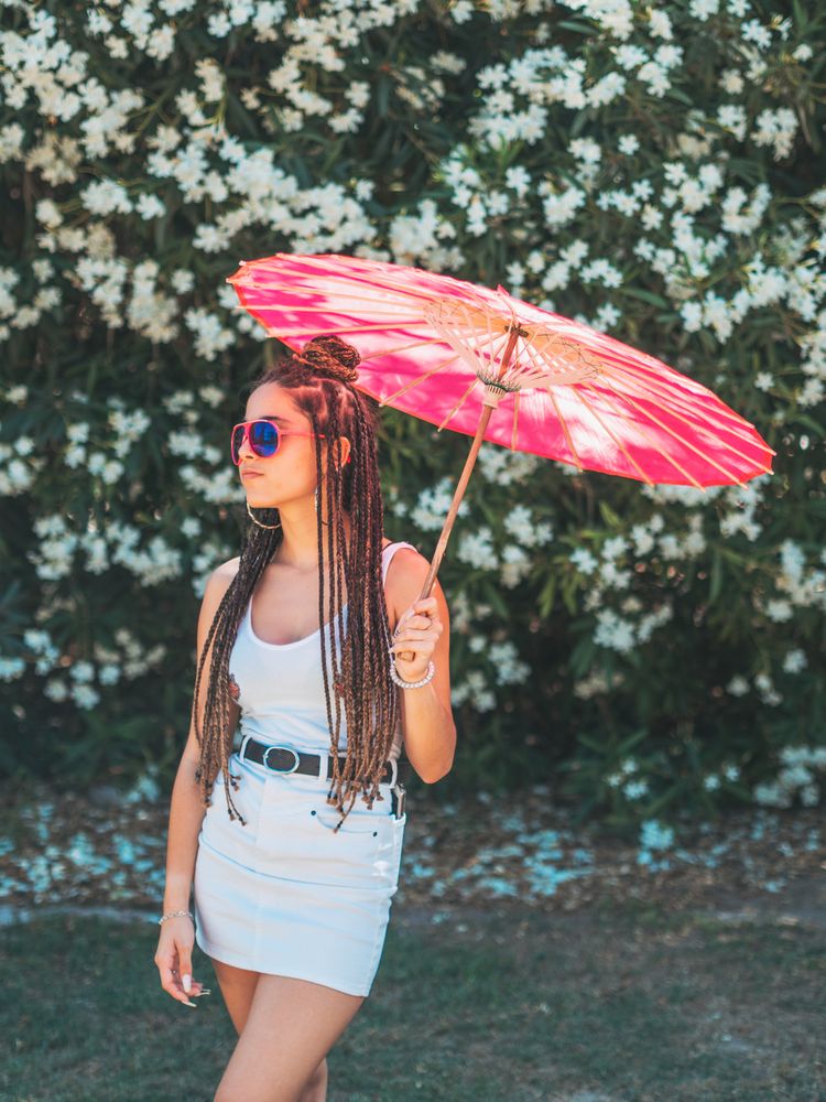 Fit young female with umbrella standing near blooming trees