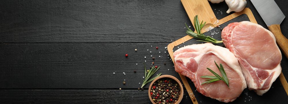 Composition with raw meat for steak and spices on wooden background