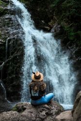 Smiling woman sitting near waterfall
