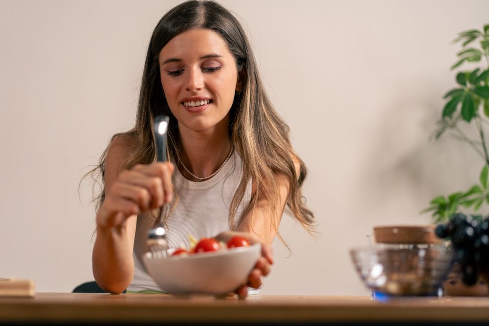 Young woman eating healthy salad fresh vegetables dinner lifestyle wellness nutrition balanced meal happy