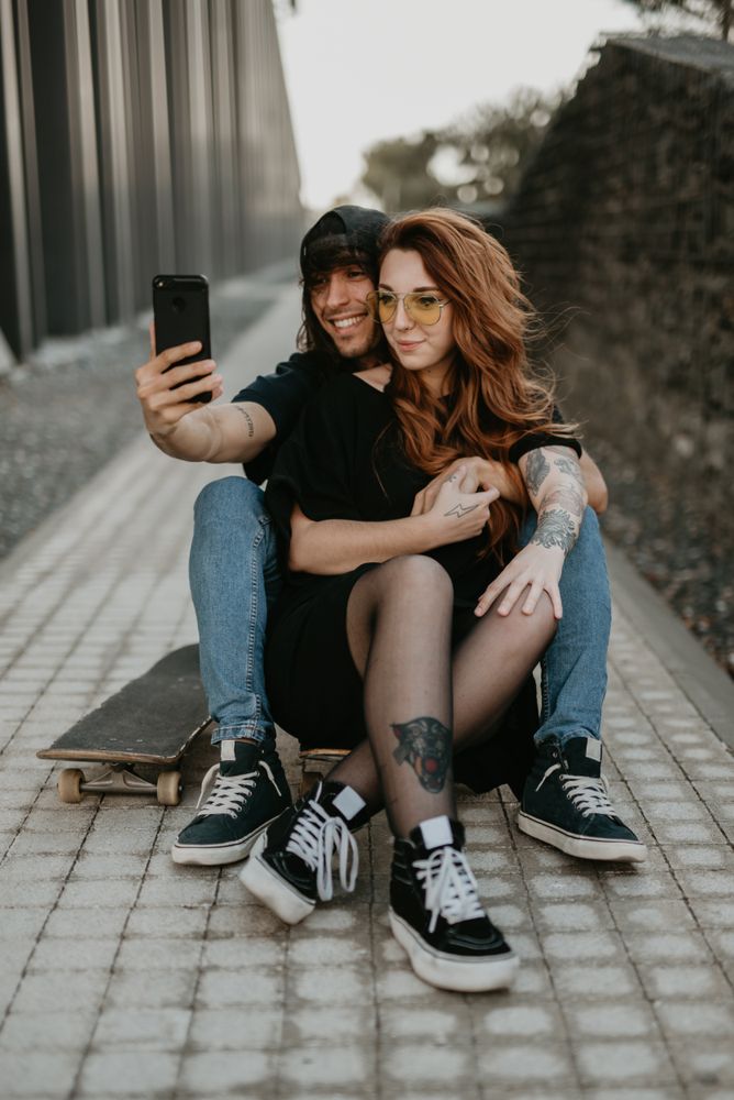 Skaters sitting on road and taking selfie on smartphone
